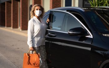 woman getting out of a car with a white mask