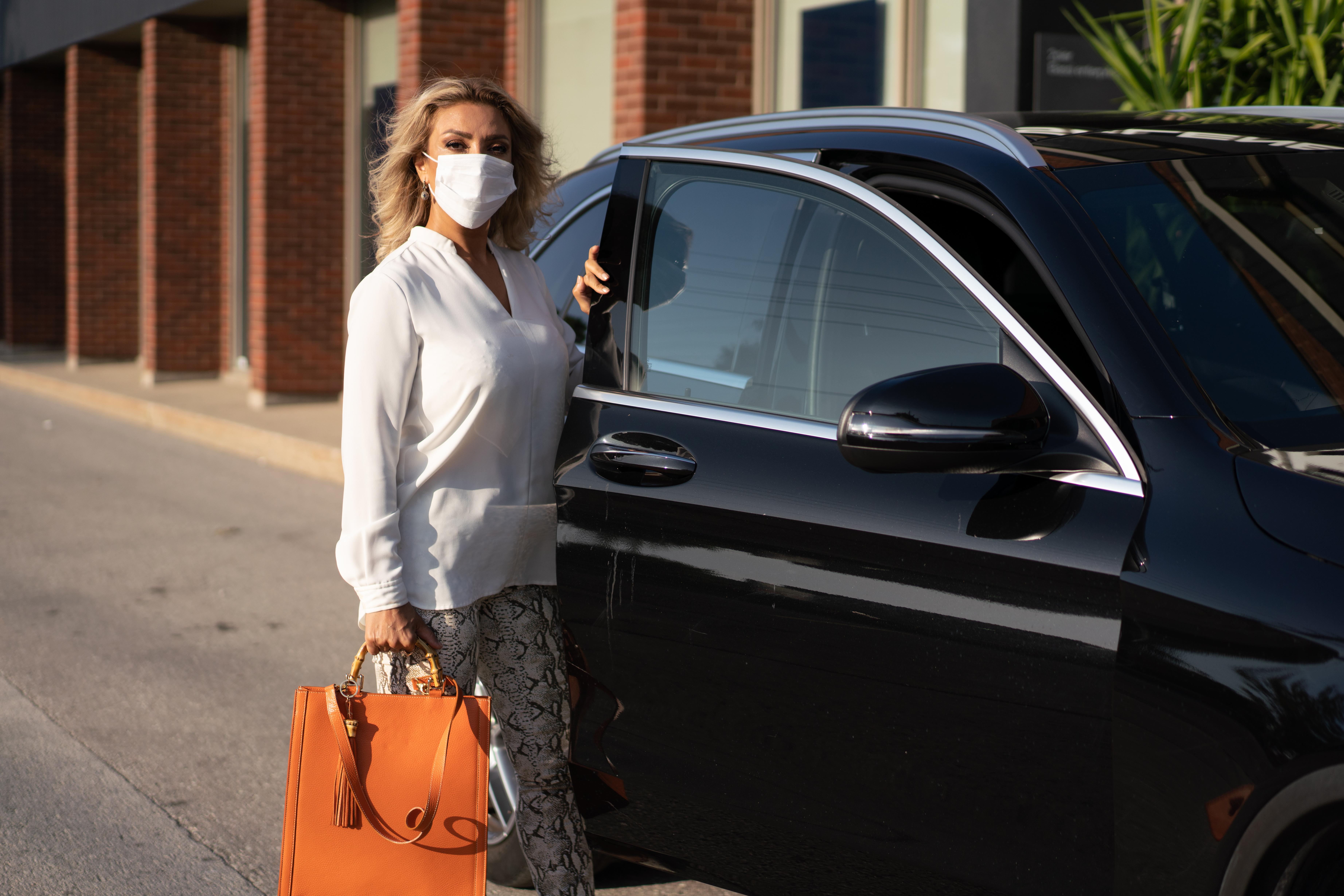 woman getting out of a car with a white mask
