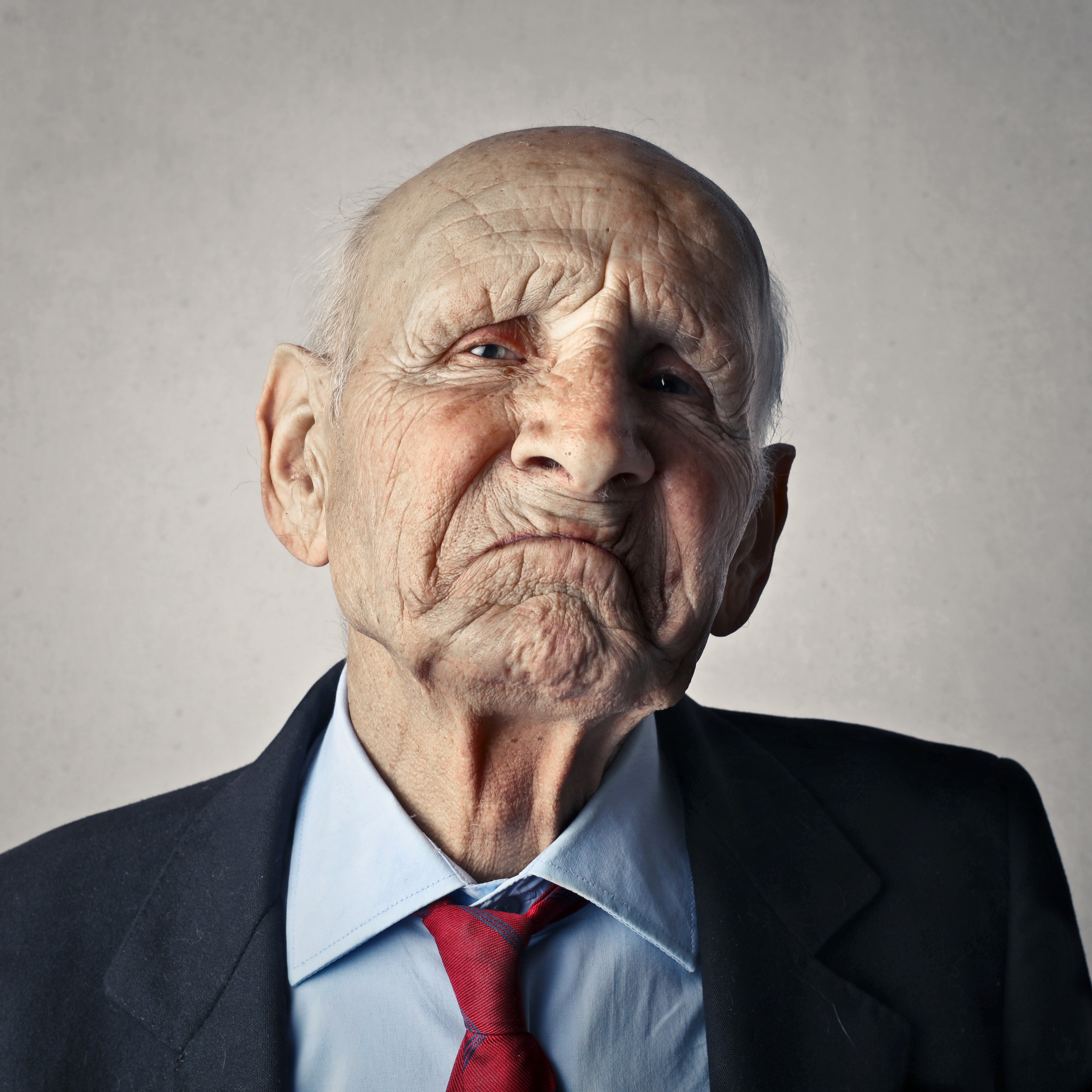 Elderly man in a suit frowning at the camera