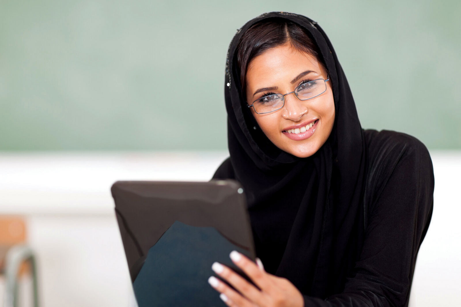 Smiling woman in a hijab holding an iPad