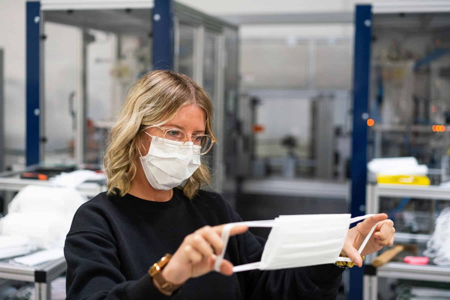 woman in a white mask examining a mask to see if its see through