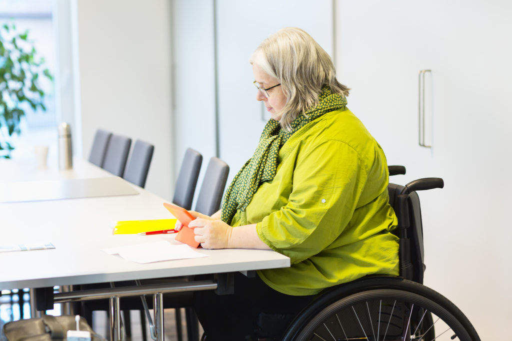 A woman in a wheelchair sitting at a conference table.
