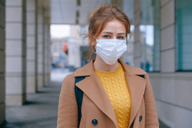 girl with light brown hair and a yellow top wearing a white mask