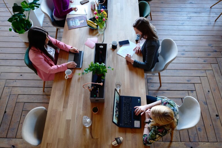 three people sitting on their computers studying