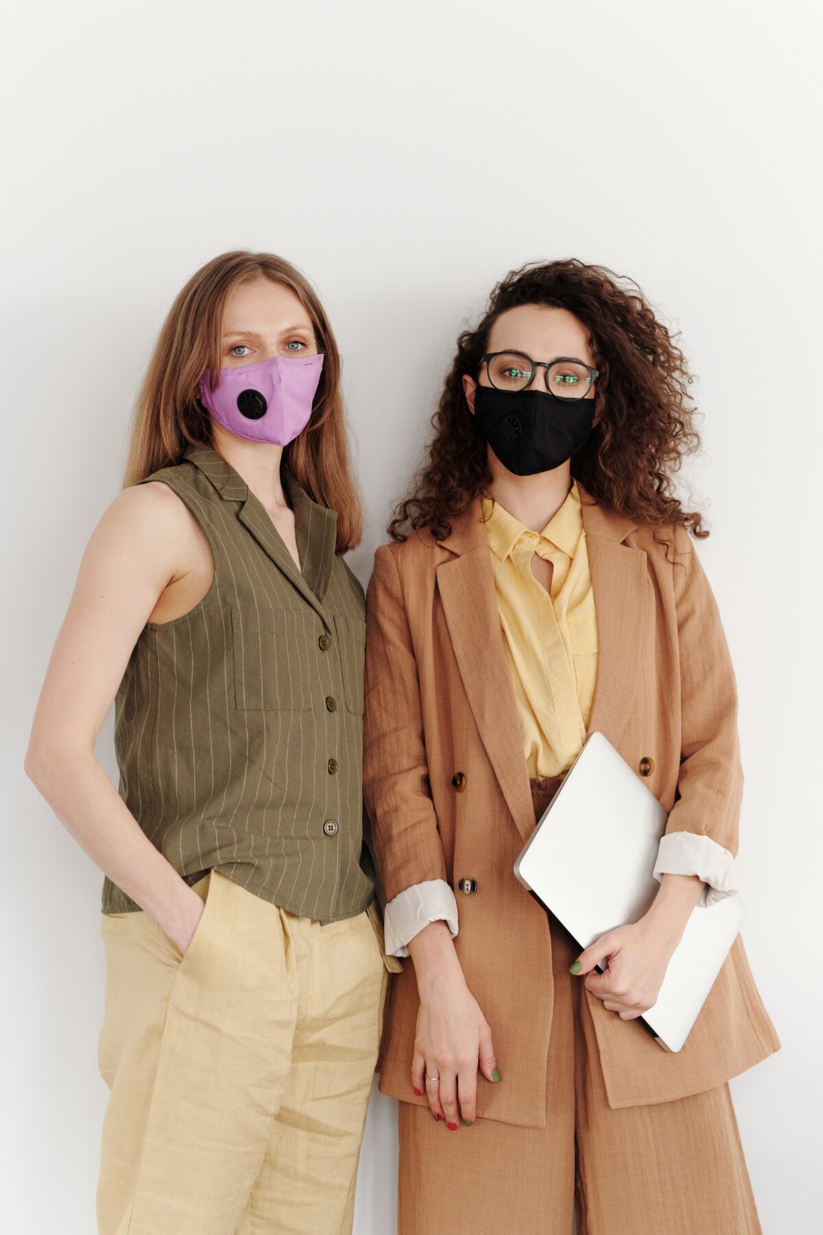 two women wearing suits, one with a purple mask and one with a black mask