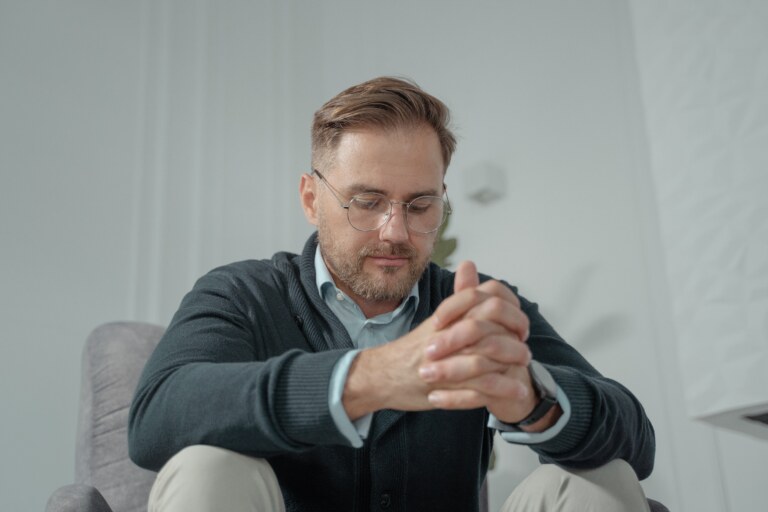 a man sitting in a chair looking at the ground