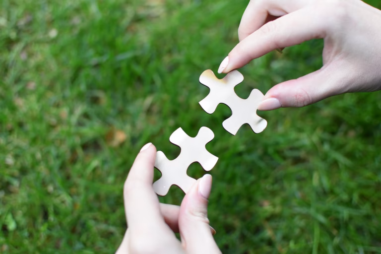 Close up of a woman's hands, each holding a puzzle piece in them.