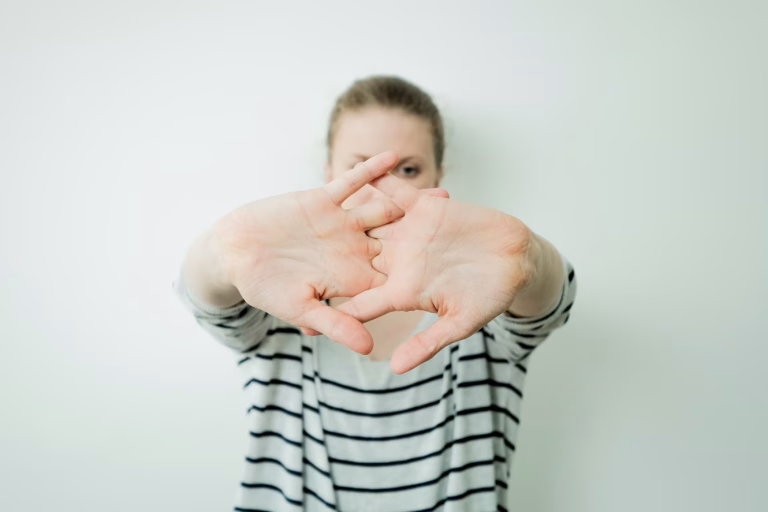 A woman in a striped sweater stretches her arms out in front of her with her fingers interlaced.