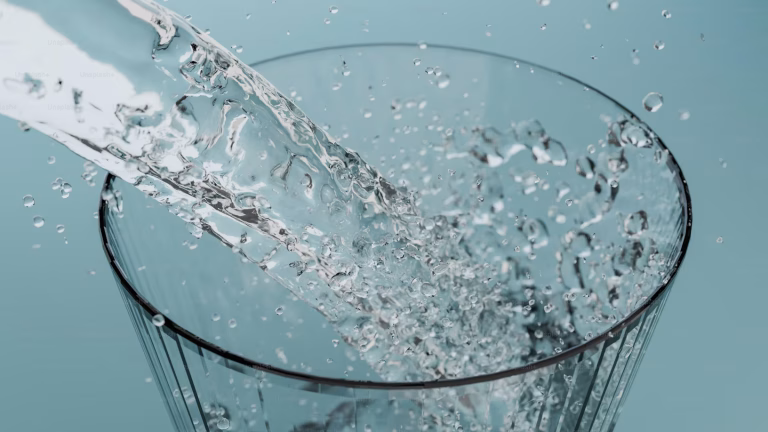 A close up view of water pouring into a clear glass.