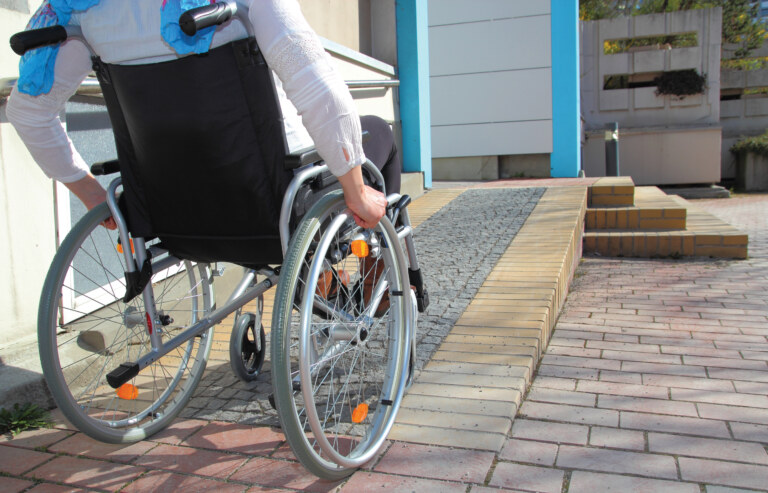 Person riding wheelchair going up a ramp